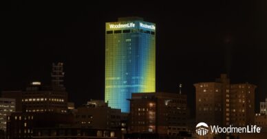 WoodmenLife Tower lit in yellow and teal