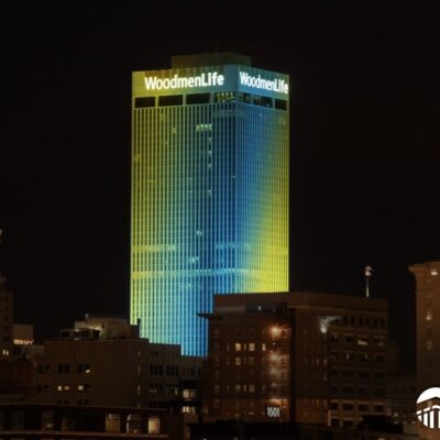 WoodmenLife Tower lit in yellow and teal